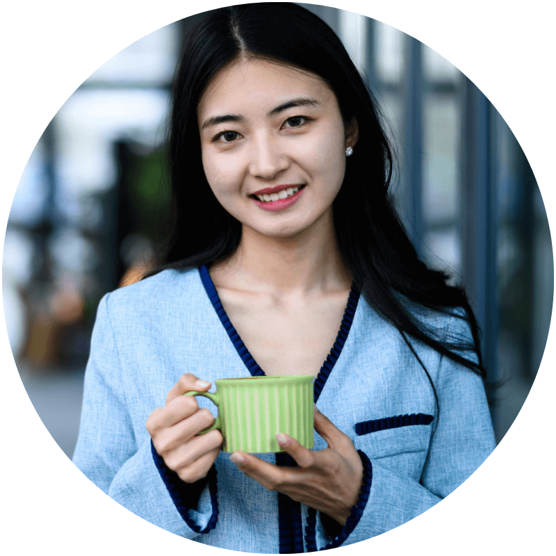 A female young adult smiling at the camera while holding a cup of tea