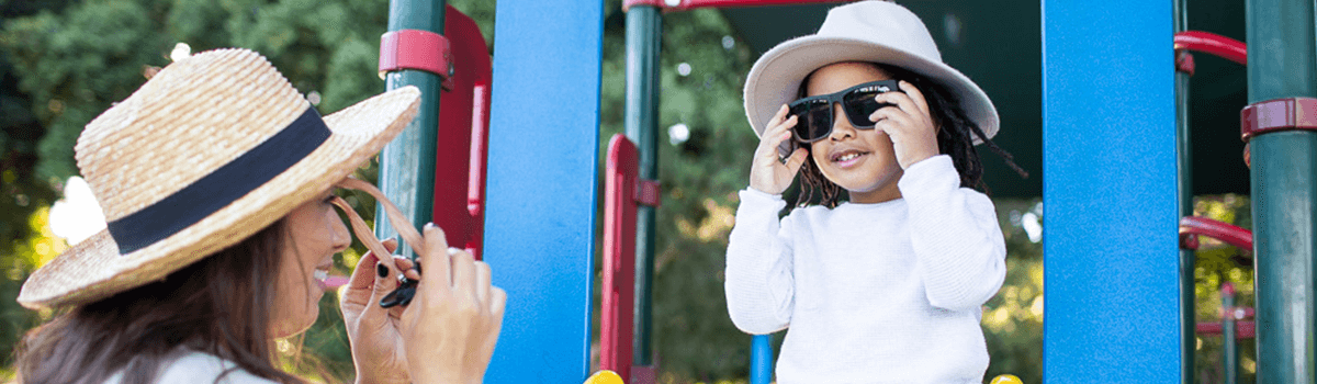 A woman and child put on their sunglasses at the playground