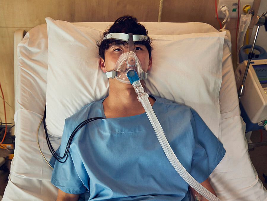 A young man lies in a hospital bed getting treatment for lung damage caused by vaping