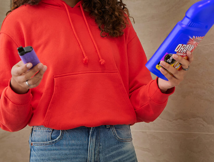 A young woman holds a vape and cleaning disinfectant which contains some of the same chemicals as what's in a vape
